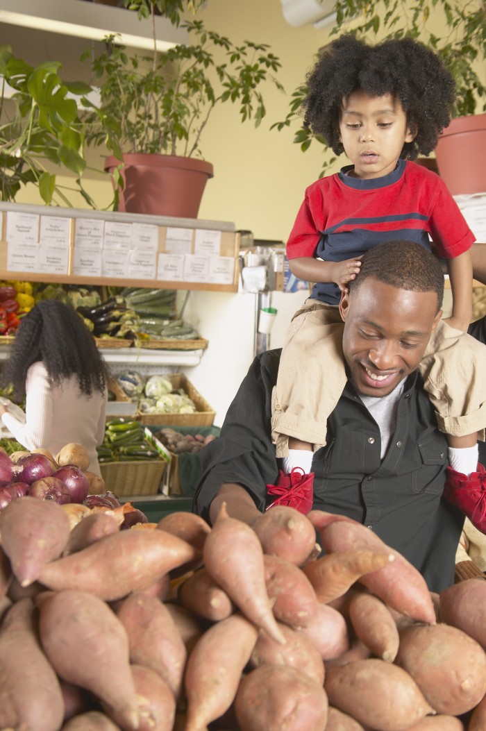 African American father with young son on shoulders in supermarket
